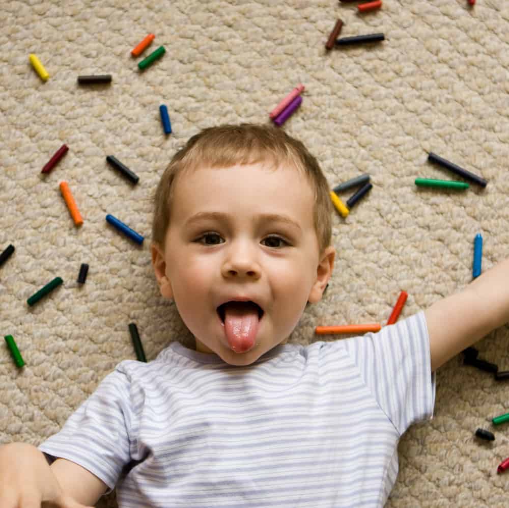 Silly kids playing with crayons on carpet